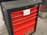une boîte à outils noire et rouge posée sur le trottoir