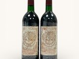 two bottles of red wine sitting next to each other on a white surface