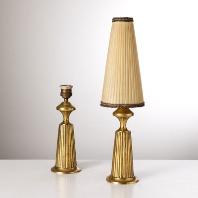 une paire de lampes de table en laiton avec des abat-jours en plis, posées sur une surface blanche