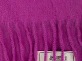 purple wool scarf with fringes on top of it on a white surface