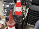 une pile de cônes de signalisation orange et blancs à côté d'une pile de pneus noirs et blancs