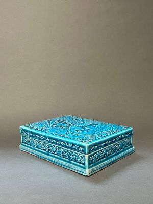 une paire de boîtes bleues et vertes ornées de motifs, posées sur une surface grise