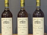 trois bouteilles de vin sont posées sur une table en bois devant un mur bleu
