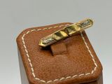 a gold tie bar sitting on top of a wooden box