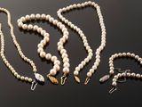 several pearl necklaces and bracelets are laid out on a black surface
