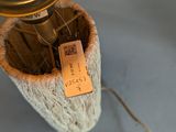 a small vase with a tag on it and a lamp on top of it