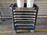 several buckets of paint are stacked on a cart in a garage