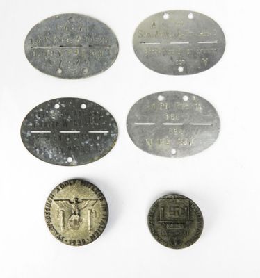 plusieurs vieilles étiquettes métalliques et une pièce de monnaie posées sur une surface blanche