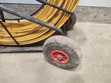 a yellow hose on a cart with a red wheel