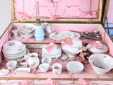 a pink suitcase with a bunch of dishes and cups in it