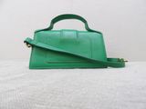 a green purse sitting on top of a bed next to a white wall