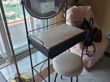 a small table with a mirror and stool in front of a window