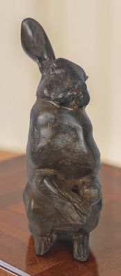 une statue représentant un lapin assis sur une table en bois