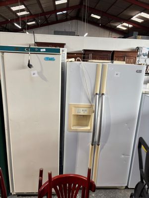 several refrigerators and freezers in a warehouse with chairs and tables
