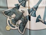 a blue and white scarf with a picture of a bird and two brooms