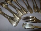 a lot of silver spoons and forks sitting on a table