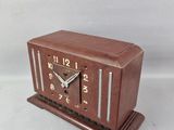 a small wooden clock on a stand on a white background