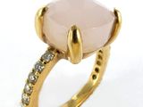 a close up of a ring with a pink stone surrounded by diamonds