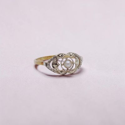 gros plan d'une bague en or avec une perle au centre