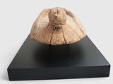 a wooden sculpture of a turtle on a black stand