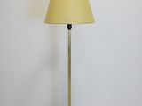 a brass floor lamp with a yellow shade on top of it