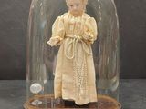 une figurine représentant une femme en robe, placée sous un dôme en verre