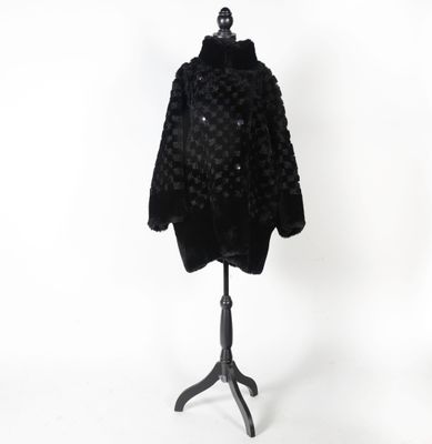 un manteau de fourrure noir posé sur un mannequin, sur fond blanc