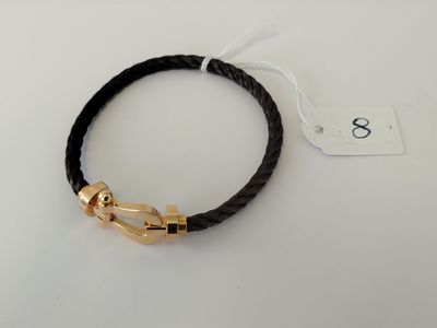 a black leather bracelet with a gold clasp on a white background