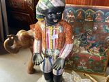 une figurine représentant un homme noir assis sur un rocher