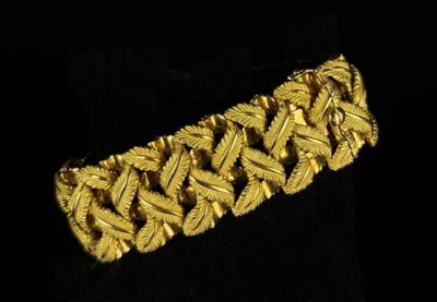 gros plan d'un bracelet en or sur une surface noire