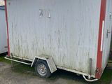 a white trailer with a red trim parked in a parking lot