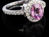 une bague ovale sertie d'un saphir rose et de diamants, posée sur un fond noir