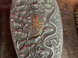 a silver spoon with a dragon on it sitting on a table