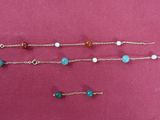 three bracelets of different colors and sizes on a pink surface