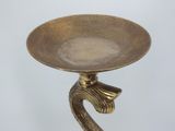 a gold plate with a bird on it on a stand