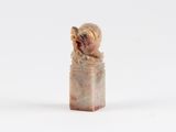 une petite figurine représentant un chien assis sur une bouteille
