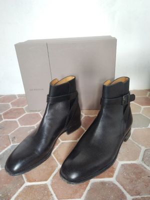 a pair of black leather boots on a tiled floor next to a box