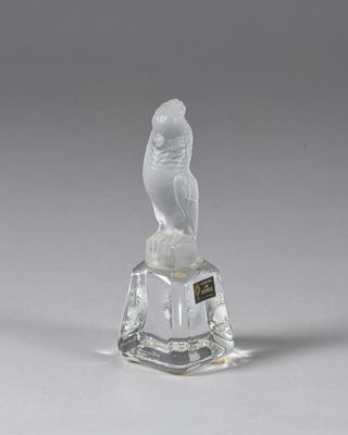 une figurine en verre représentant un oiseau, posée sur un socle en verre