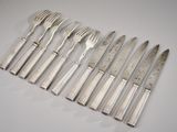 six silverplated flatware forks and knives on a white surface