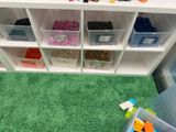 Il y a de nombreux bacs remplis de Lego par terre dans cette salle de jeux