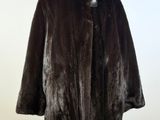 un manteau de fourrure noir posé sur un mannequin, devant un mur blanc