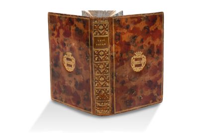 un vieux livre à la couverture décorative posé sur une surface blanche