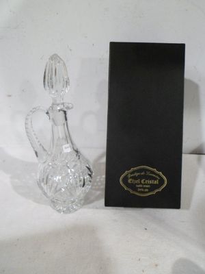 un flacon de parfum en verre et une boîte noire sur une table