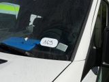 a white car with a sticker on it ' s windshield