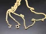 a close up of a gold chain with two charms on it