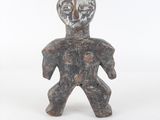une vieille figurine représentant un homme debout sur une surface blanche