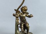 a bronze statue of a cupid holding a harp and a candle