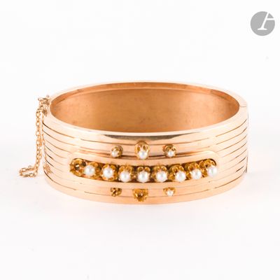 Le bracelet est en or, orné de perles et d'une chaîne qui l'entoure.