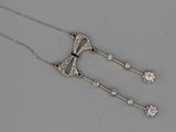 an image of a silver necklace with diamonds on a gray surface