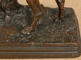 bronze statue of a dog and a cat sitting on a rock